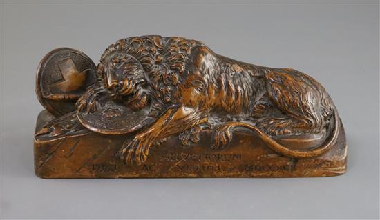 A late 18th century wood carving of a lion recumbent upon military trophies, 9.25in.